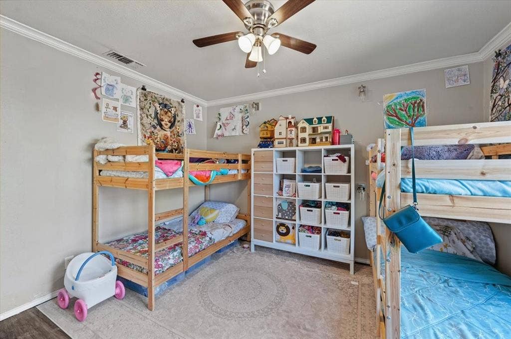 809 W Bridge Street, Weatherford, TX 76086 Neutral wall color, crown molding, wood-finish flooring, ceiling fan with integrated lighting, and a cubby storage unit