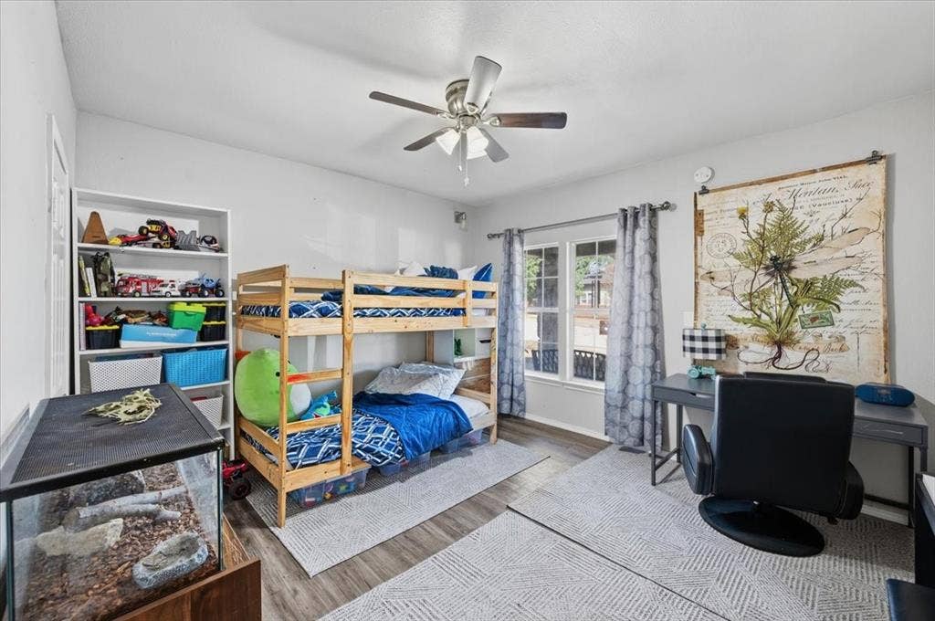 809 W Bridge Street, Weatherford, TX 76086 Spacious room featuring wood-finish flooring, a contemporary ceiling fan, and a large window with drapes