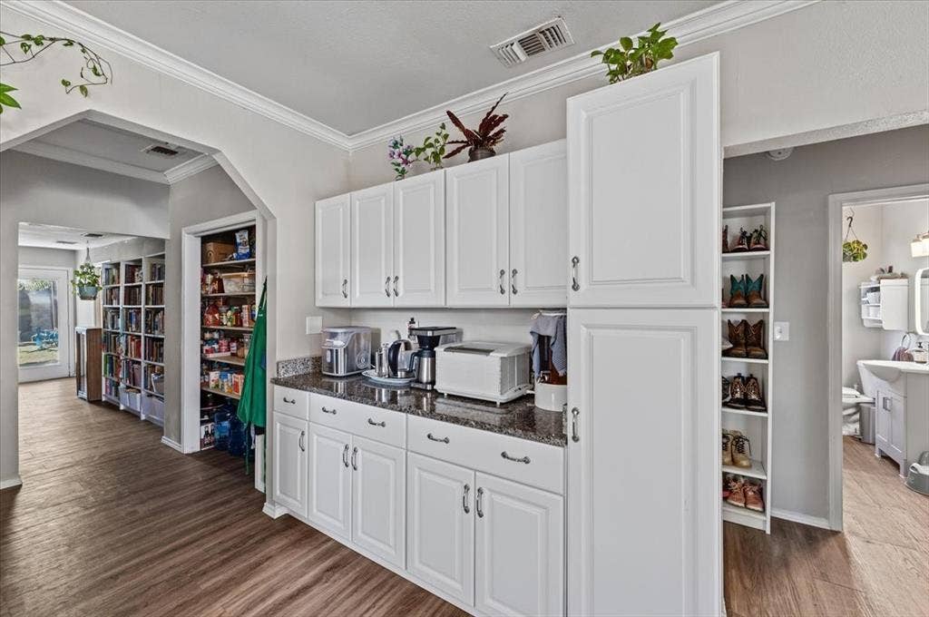 809 W Bridge Street, Weatherford, TX 76086 White cabinetry with brushed nickel hardware, granite-style countertops, wood-finish flooring, and pantry storage