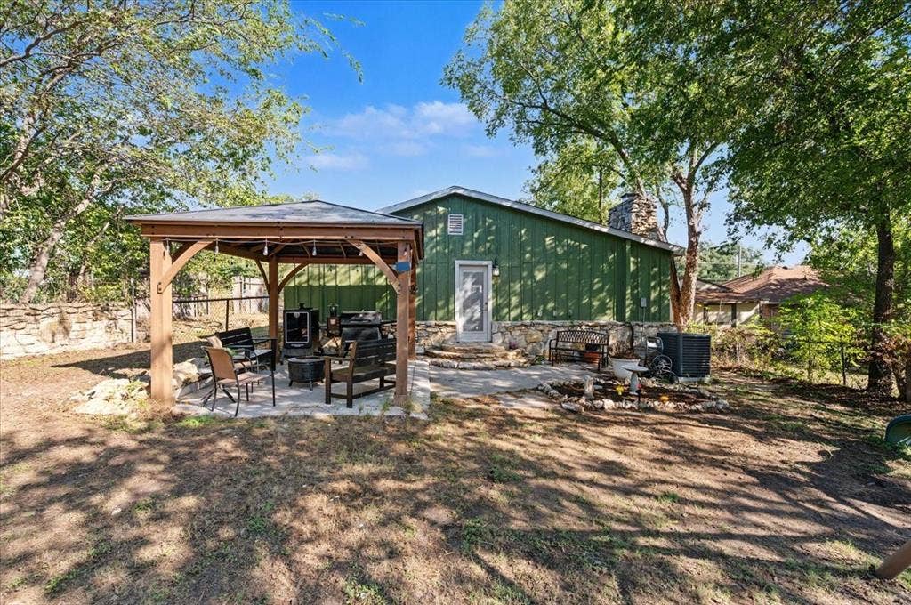 809 W Bridge Street, Weatherford, TX 76086 Exterior featuring green siding, stone accent base, and a stone chimney