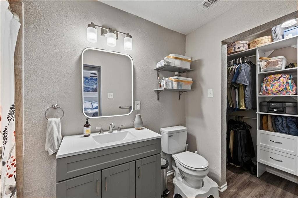 809 W Bridge Street, Weatherford, TX 76086 Gray vanity with integrated sink, rectangular illuminated mirror, and brushed nickel fixtures