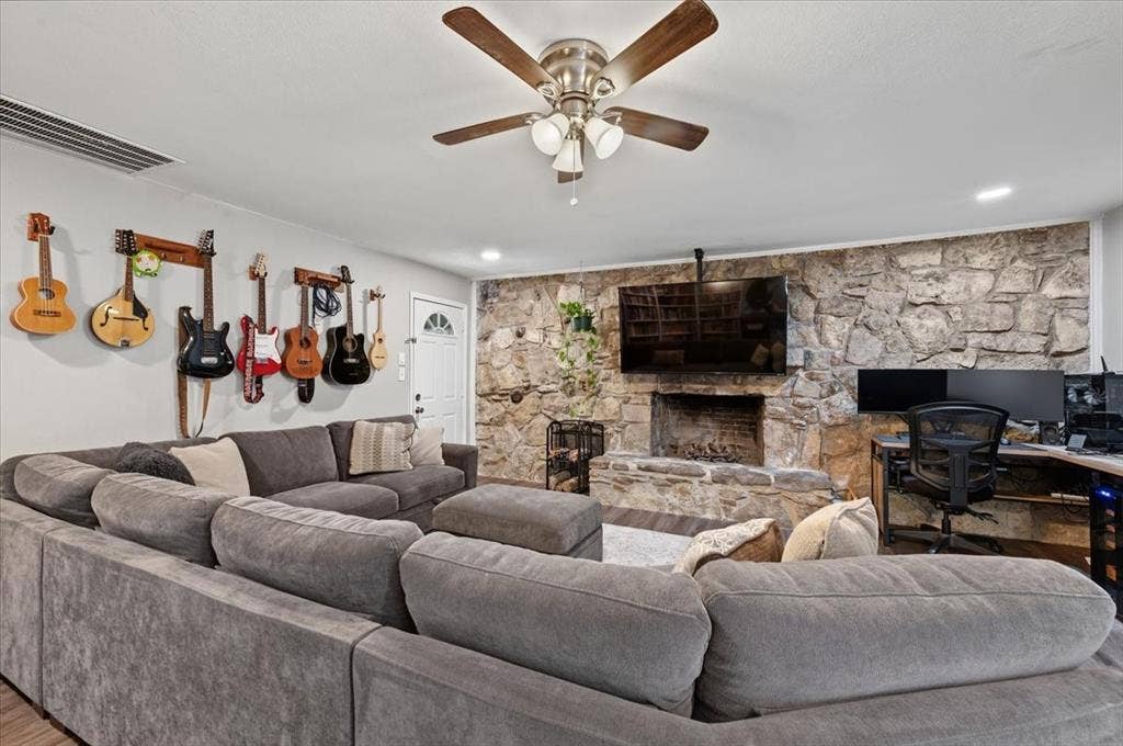 809 W Bridge Street, Weatherford, TX 76086 Stone-clad fireplace with hearth, wood-finish flooring, ceiling fan with integrated lighting, and recessed ceiling lighting