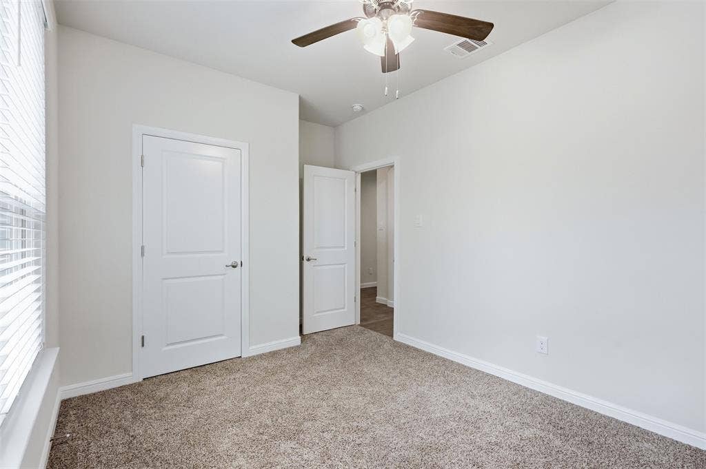 9005 Fescue Drive, Fort Worth, TX 76179 Neutral tone wall paint, textured carpeting, contemporary ceiling fan, bright white trim, and paneled interior doors