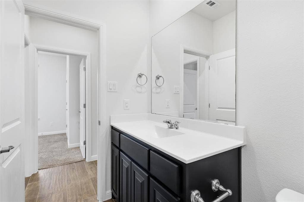 9005 Fescue Drive, Fort Worth, TX 76179 Modern vanity featuring a single basin sink, chrome faucet, and dark wood-finish cabinetry