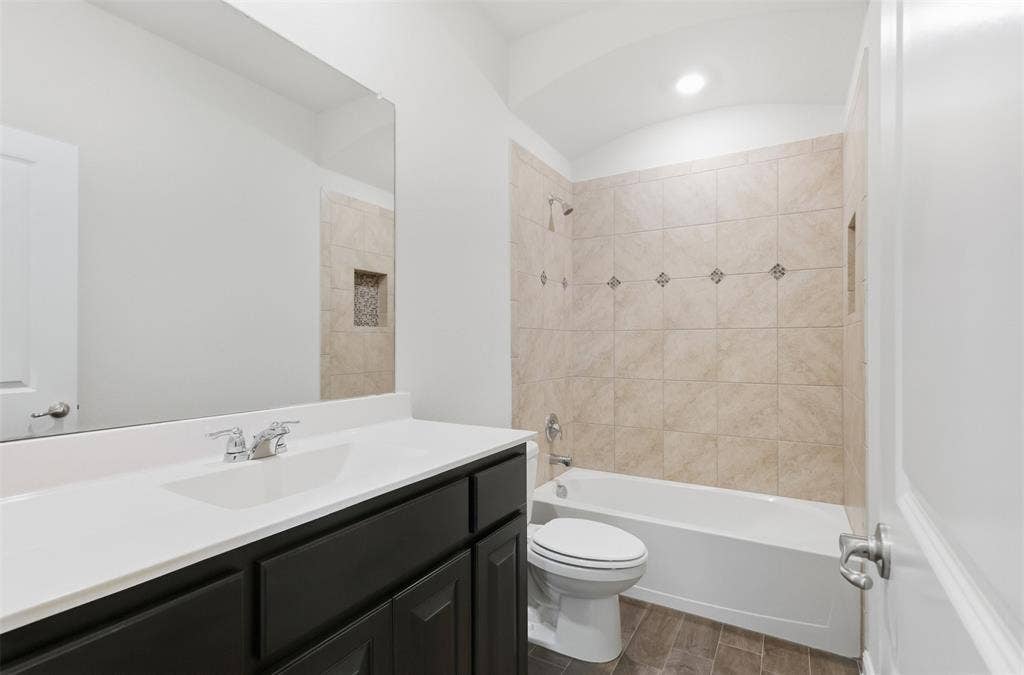 9005 Fescue Drive, Fort Worth, TX 76179 White vanity with a rectangular undermount sink, a large mirror, and a tiled shower-tub combination