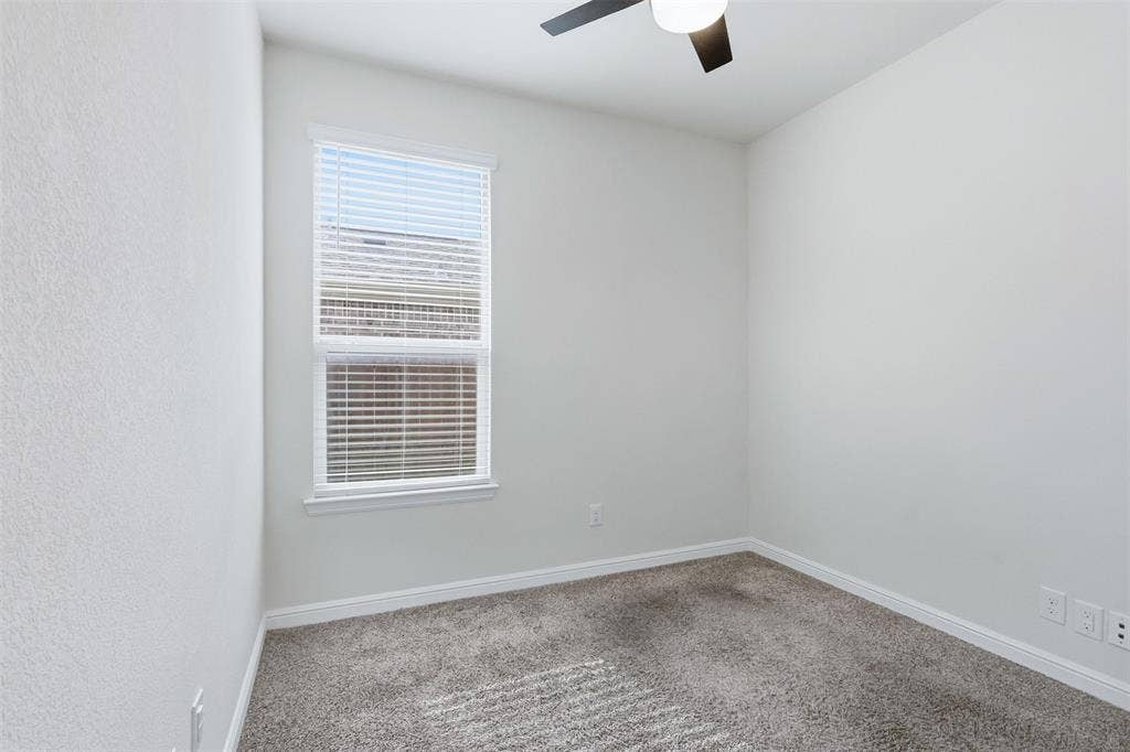 9005 Fescue Drive, Fort Worth, TX 76179 Neutral tone walls, window with blinds, dark-toned ceiling fan, and carpeted flooring