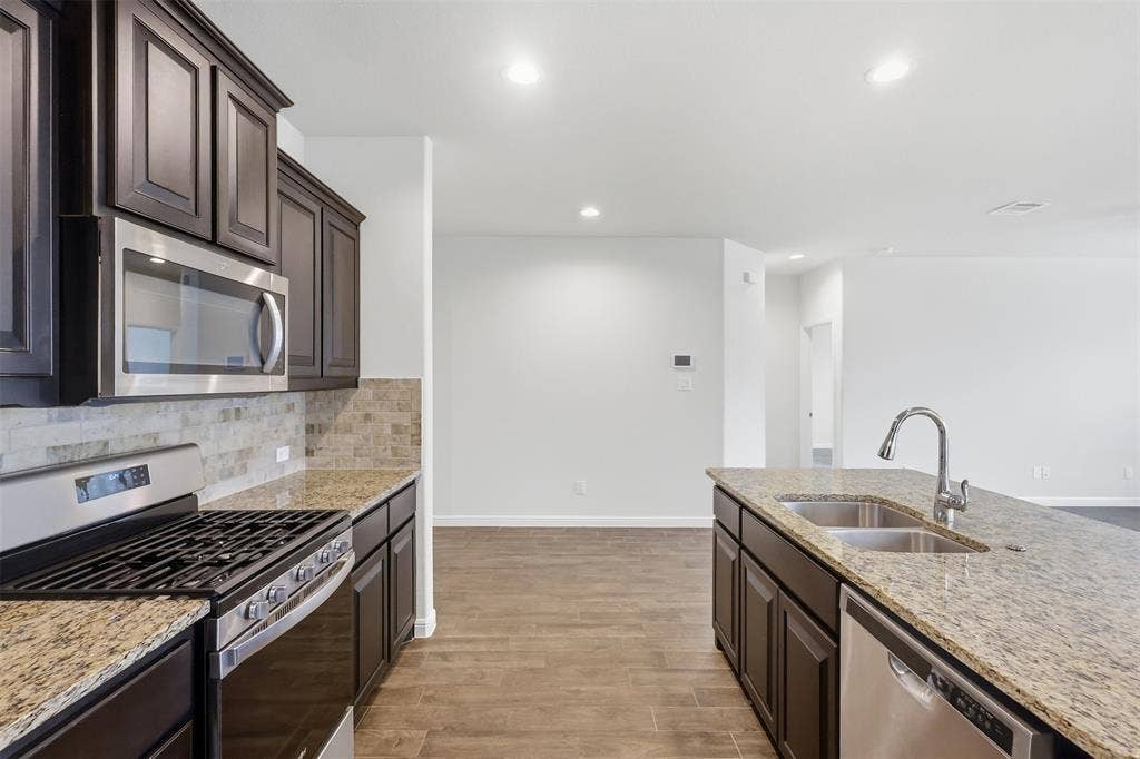 9005 Fescue Drive, Fort Worth, TX 76179 Kitchen featuring a stainless steel gas range, over-range microwave, double basin sink, and Tile flooring
