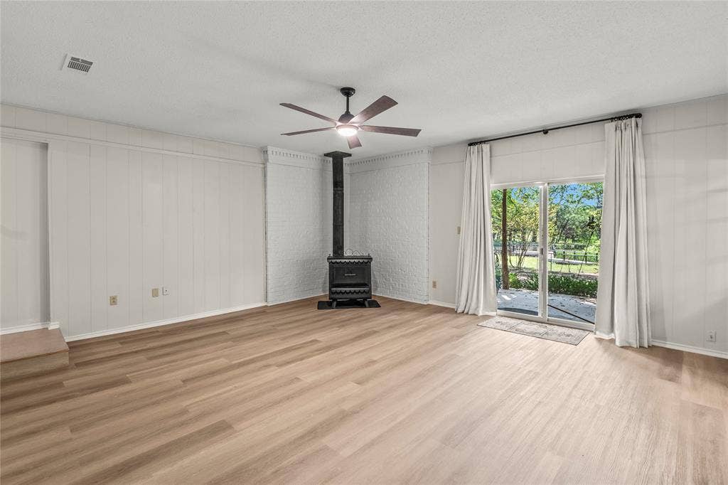 125 Harrell Street, Gun Barrel City, TX 75156 Spacious family room freshly painted with with new luxury vinyl plank flooring, new fixtures andwood burning stove.