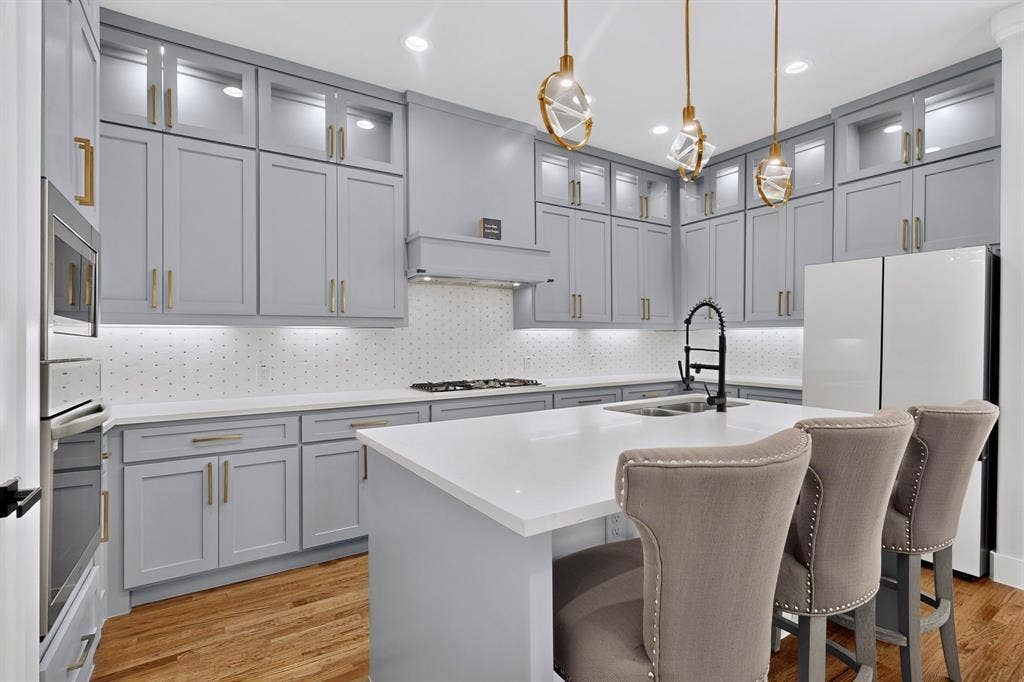 518 Crete Street, Dallas, TX 75203 Light gray cabinetry with gold-tone hardware, white countertops, built-in stainless steel appliances, and wood-finish flooring
