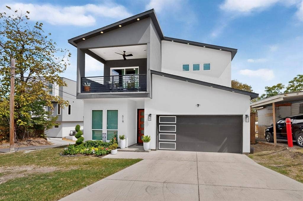 518 Crete Street, Dallas, TX 75203 Contemporary facade with a covered second-story balcony featuring a ceiling fan, a modern garage door with frosted glass panels, an accent-colored entry door, and a concrete driveway