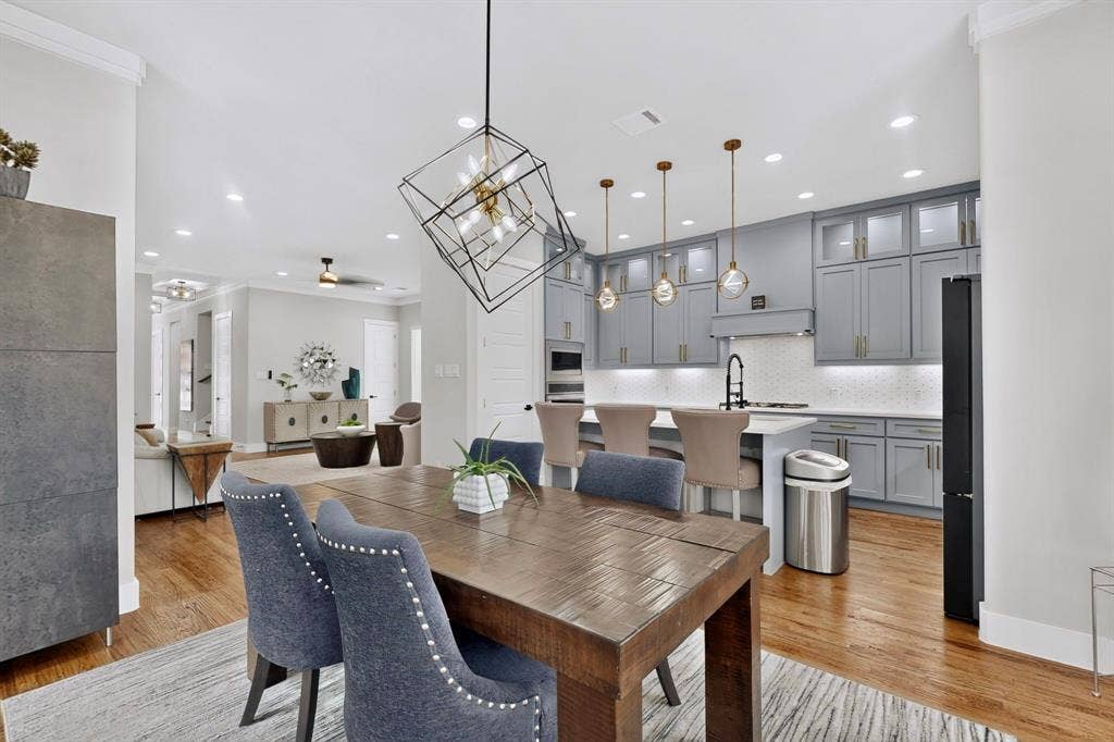518 Crete Street, Dallas, TX 75203 Wood-finish flooring throughout, modern kitchen with gray cabinetry, kitchen island with seating, geometric lighting fixture, and recessed lighting