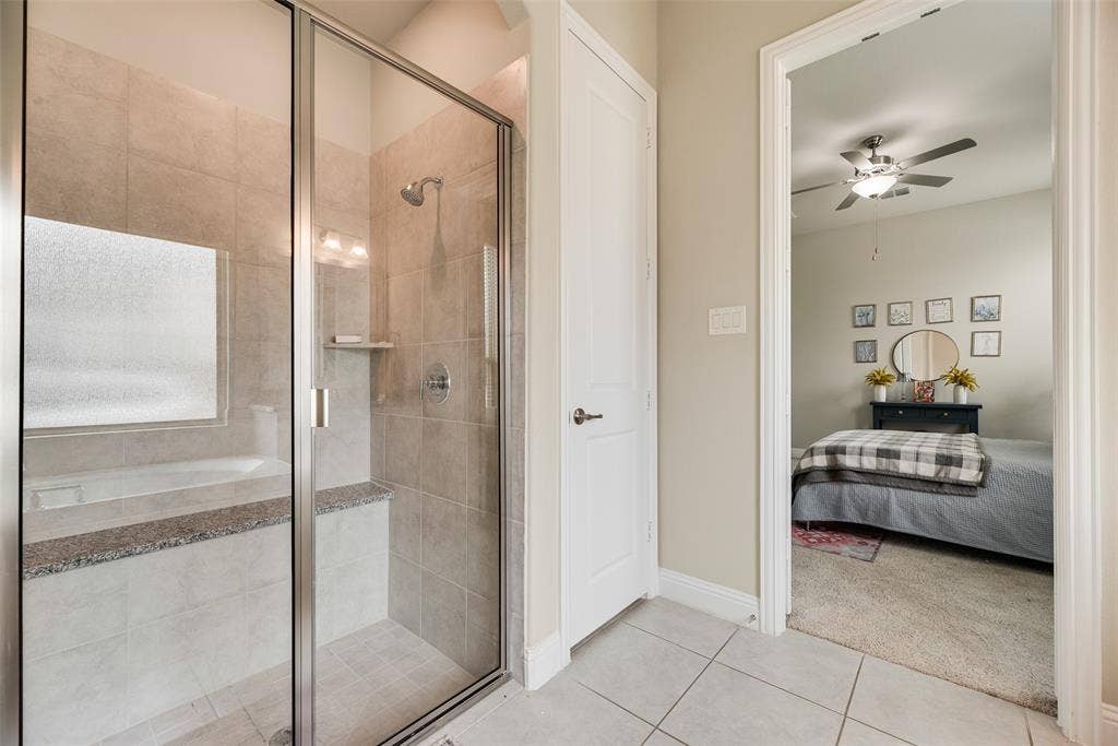 718 Waterbrook Parkway, Argyle, TX 76226 Glass-enclosed shower with a built-in bench, tiled walls, and a separate soaking tub