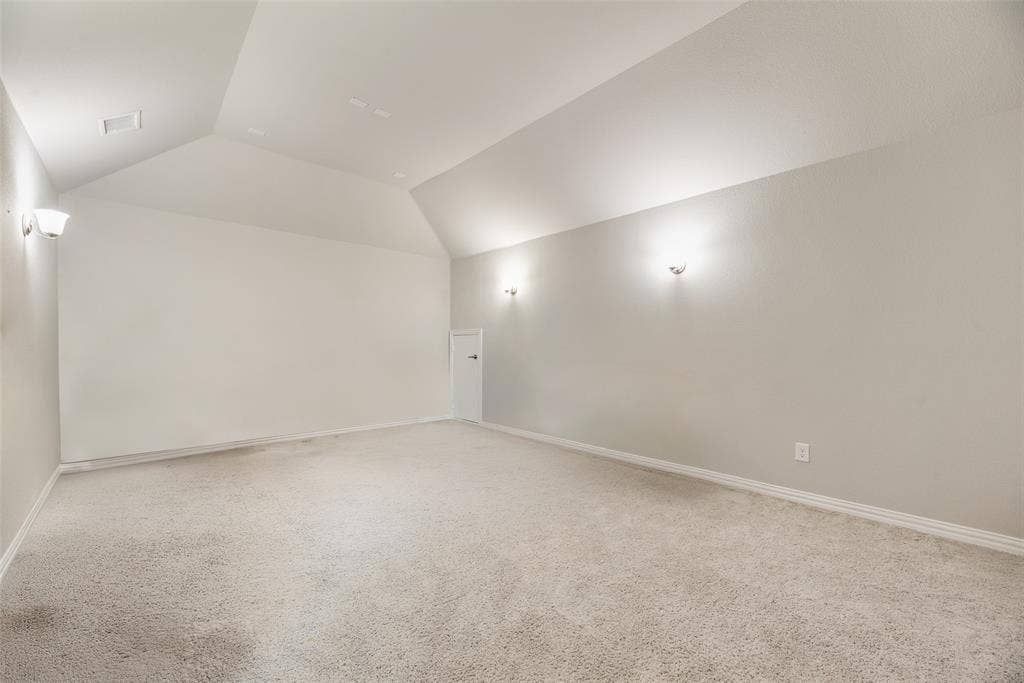 718 Waterbrook Parkway, Argyle, TX 76226 Carpeted flooring, vaulted ceiling, white walls, wall sconces, and a white door