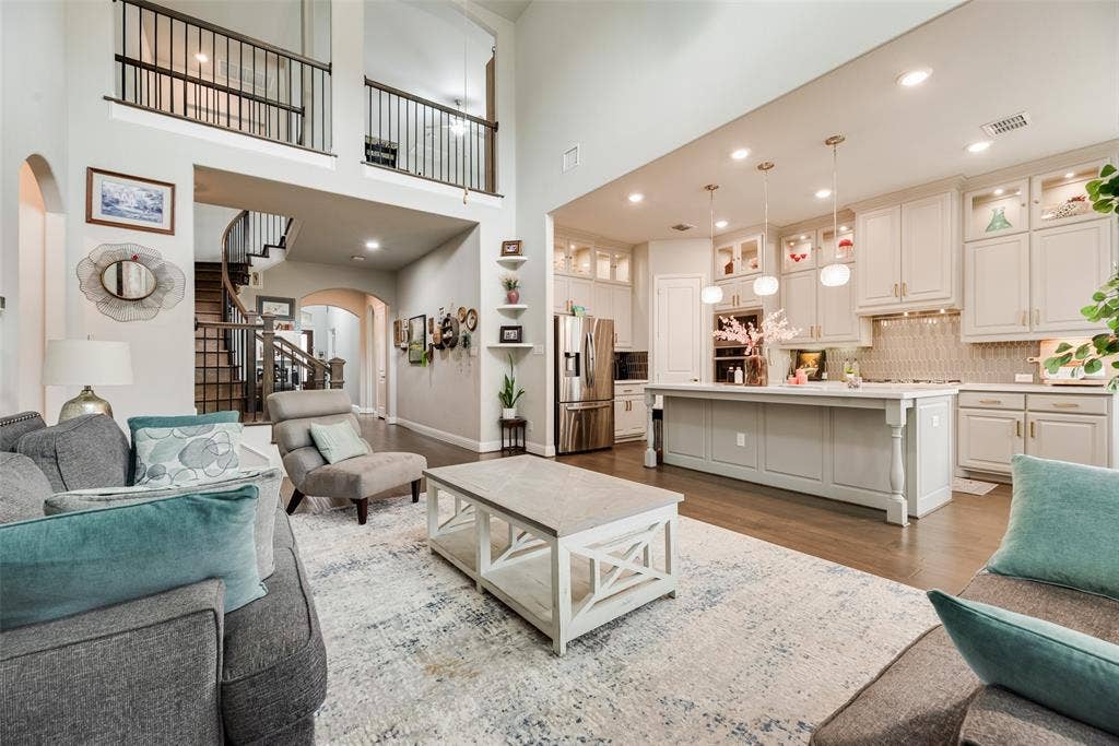 718 Waterbrook Parkway, Argyle, TX 76226 Two-story great room with a spiral staircase, wood-finish flooring, and a kitchen featuring a large island, pendant lighting, and stainless steel appliances