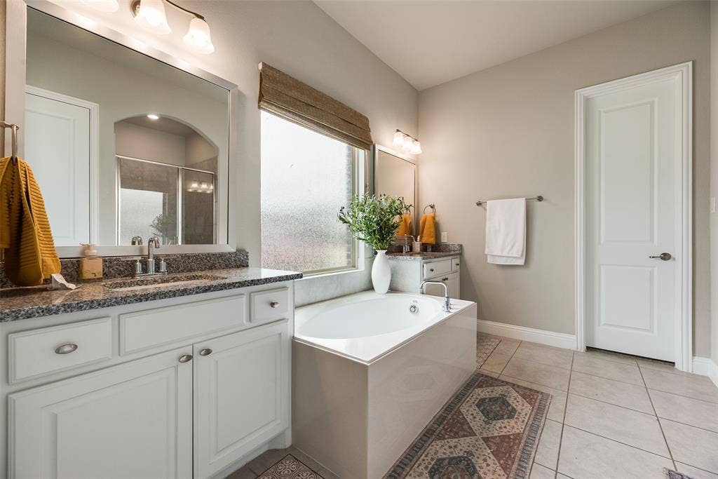 718 Waterbrook Parkway, Argyle, TX 76226 Dual vanity with granite countertops, a built-in soaking tub, tile flooring, and a walk-in shower with a glass enclosure