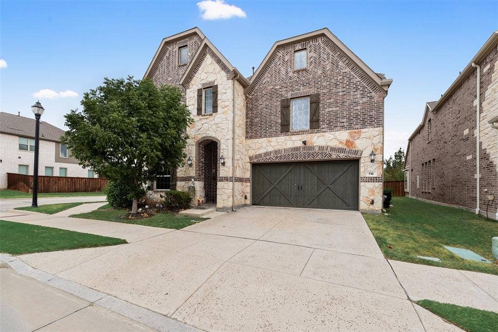 718 Waterbrook Parkway, Argyle, TX 76226 Stone and brick exterior with wood shutters, arched entry, and an attached garage with a wood-finish door