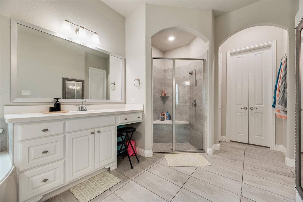 718 Waterbrook Parkway, Argyle, TX 76226 Bathroom featuring a double-door closet, a vanity with ample counter space, an integrated sink, and a walk-in shower with a built-in bench