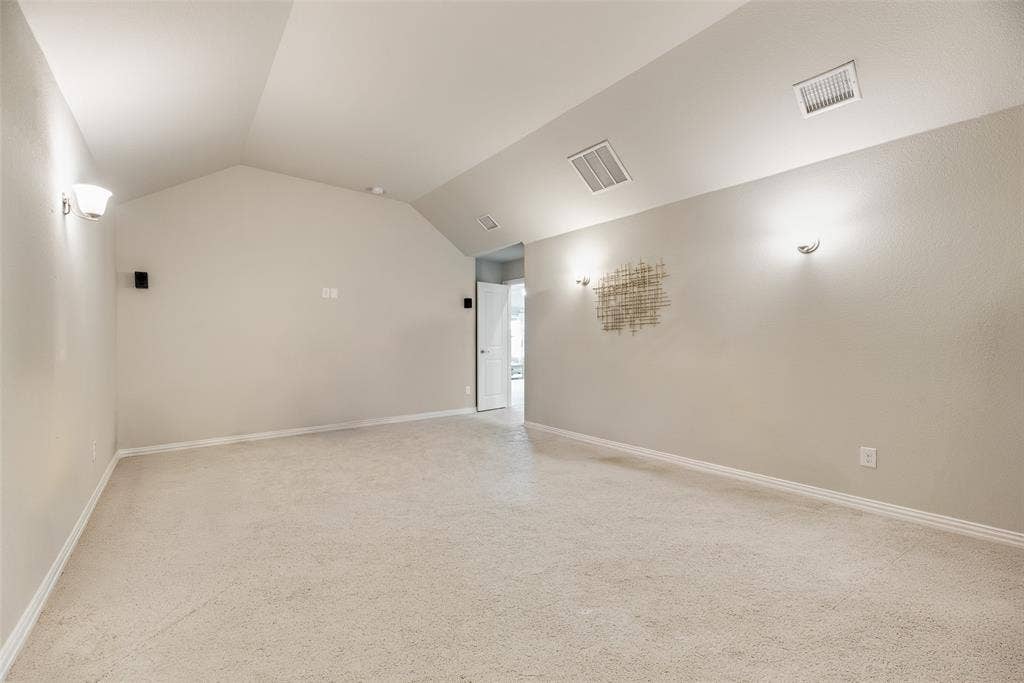 718 Waterbrook Parkway, Argyle, TX 76226 Carpeted room featuring a vaulted ceiling and wall-mounted sconces