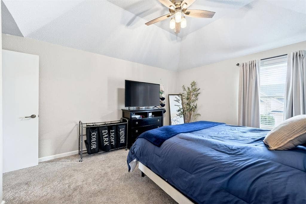 Vaulted ceiling, ceiling fan with light fixture, carpeted flooring, window with blinds, and white door