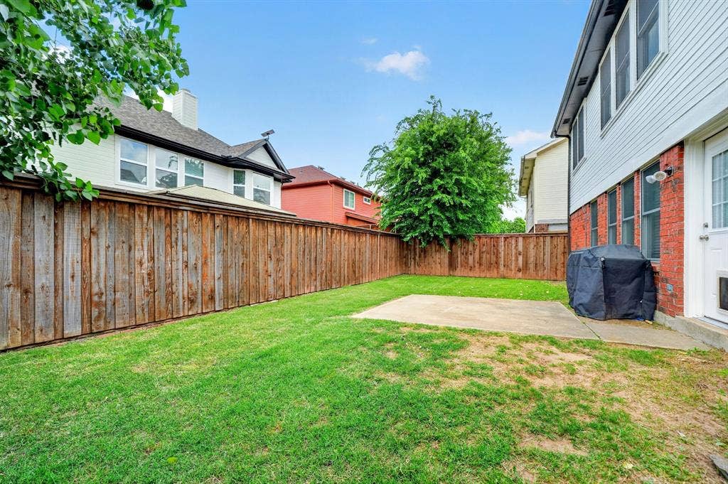 Fenced backyard with a concrete patio and a grass lawn