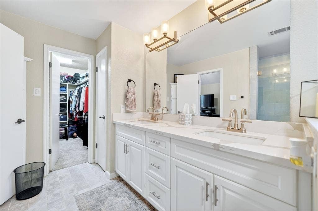 Double vanity with white cabinetry, integrated sinks, brushed nickel faucets, and a full-width mirror