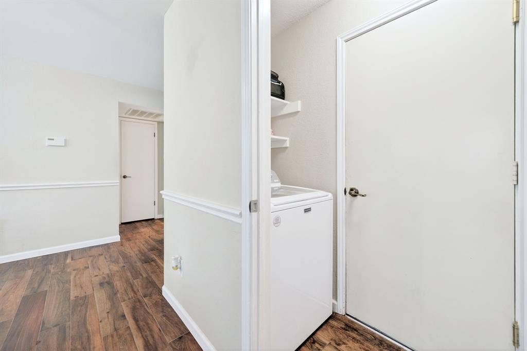 Wood-finish flooring throughout, white wall paneling, and white interior doors