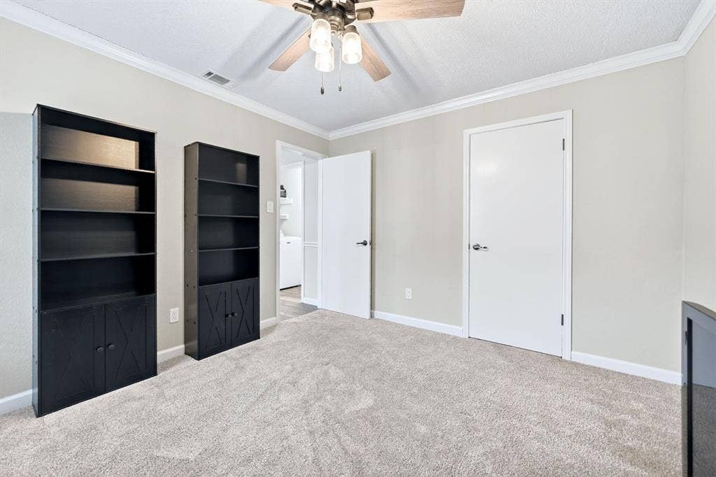 Neutral tone walls with crown molding, ceiling fan, and carpeted flooring
