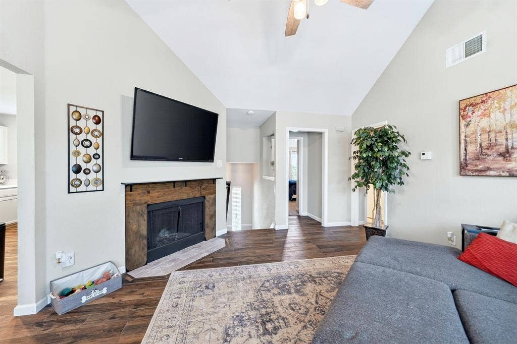 Vaulted ceiling with a ceiling fan, fireplace with a wood mantel, wood-finish flooring, and recessed lighting