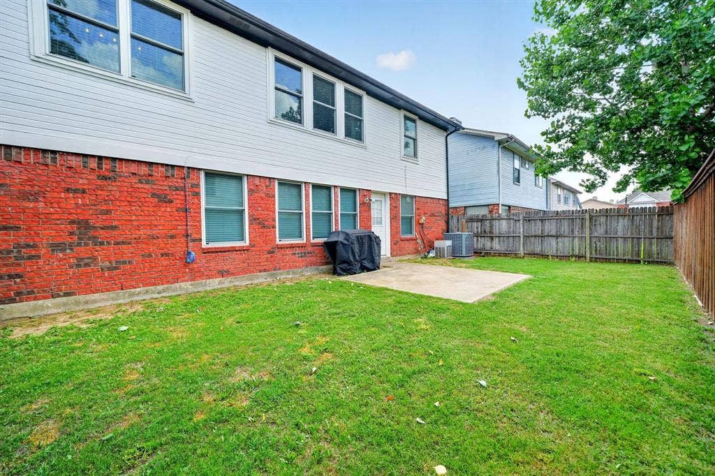 Spacious lawn with a concrete patio, bordered by a wooden privacy fence