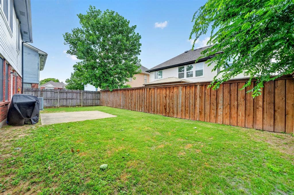 Expansive backyard featuring a lush lawn, concrete patio, and privacy fencing