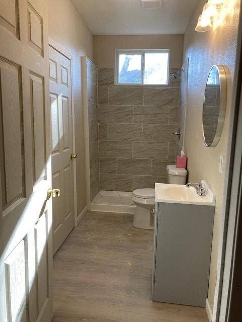 608 Turner Street, Waco, TX 76704 Bathroom featuring wood-finish flooring, a contemporary vanity with an integrated sink, and a tiled shower surround