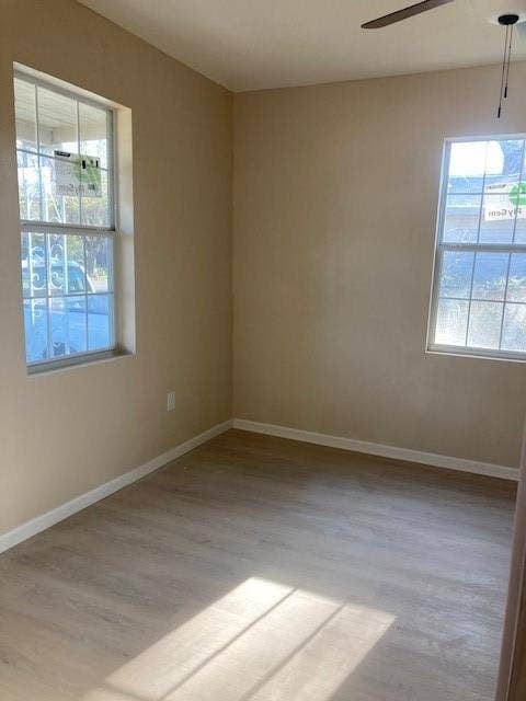 608 Turner Street, Waco, TX 76704 Neutral tone wall finishes, two windows with gridded panes, wood-finish flooring, and a ceiling fan