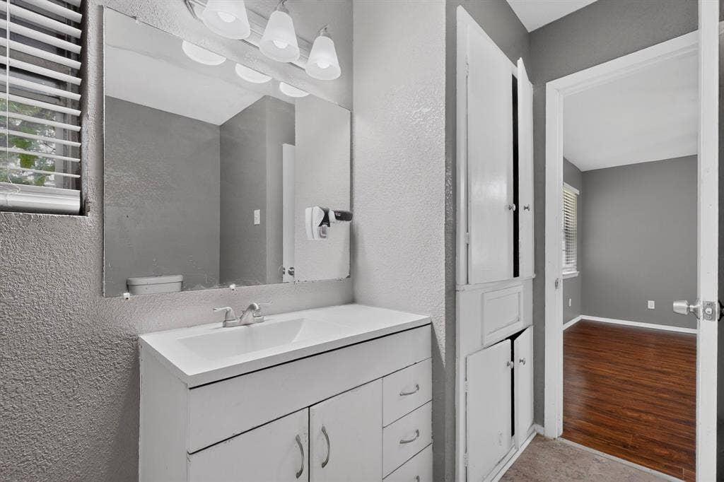 101 Spinner Circle, DeSoto, TX 75115 Vanity with integrated sink, wall-mounted mirror, and overhead light fixture