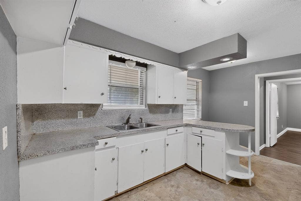101 Spinner Circle, DeSoto, TX 75115 Bright kitchen featuring white cabinetry, speckled stone countertops, stainless steel sink with single-handle faucet, and tile backsplash
