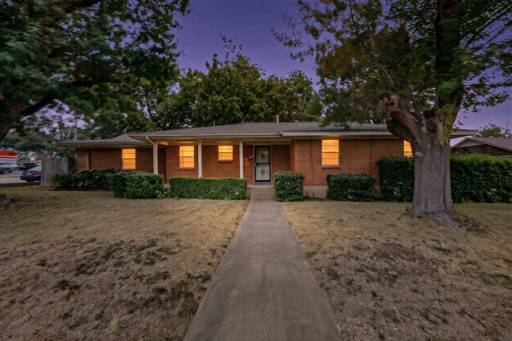 101 Spinner Circle, DeSoto, TX 75115 Brick exterior with a covered porch entry, mature front yard trees, and a concrete pathway