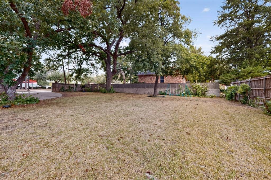 101 Spinner Circle, DeSoto, TX 75115 Expansive outdoor space featuring a large lawn area, mature trees, and a wooden privacy fence
