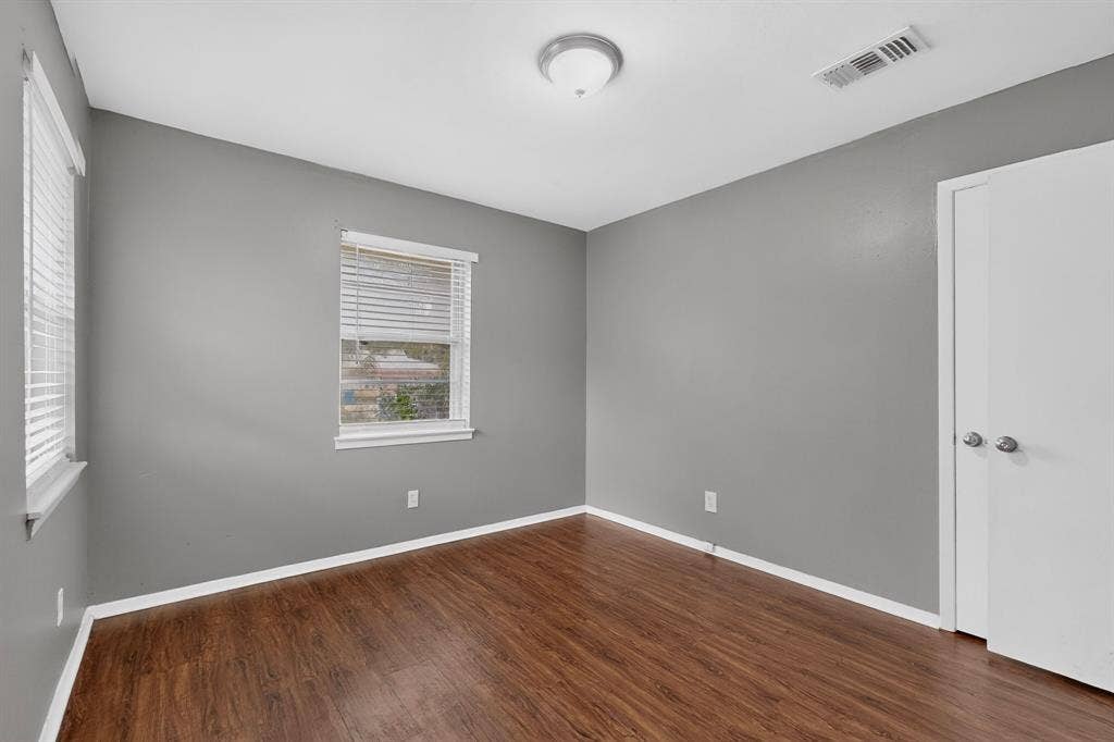 101 Spinner Circle, DeSoto, TX 75115 Wood-finish flooring, neutral gray wall tones, white trim, two windows with blinds, and a ceiling-mounted light fixture