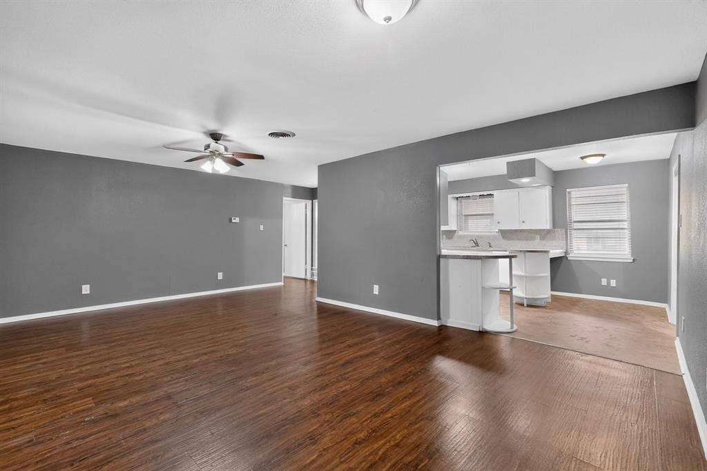101 Spinner Circle, DeSoto, TX 75115 Open-concept living space featuring warm wood-finish flooring throughout, ceiling fan with integrated lighting, and gray-painted walls