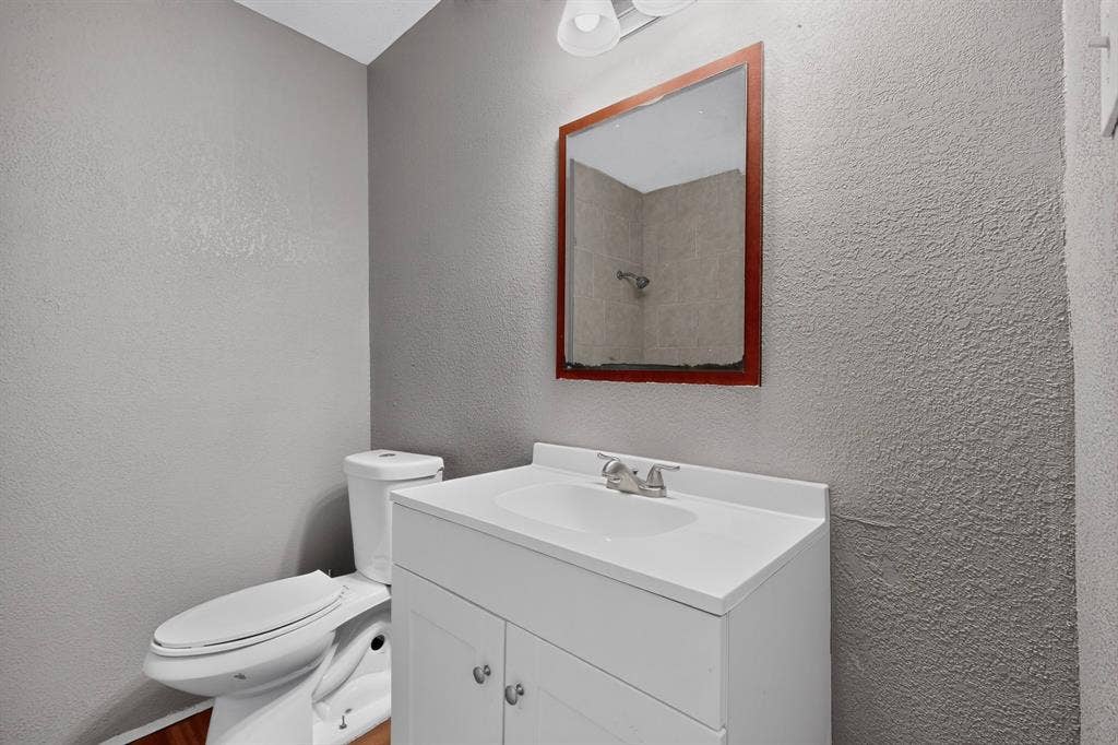 101 Spinner Circle, DeSoto, TX 75115 Bathroom featuring a single vanity with storage, a wall-mounted mirror, and a toilet