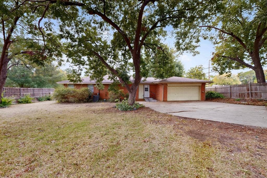 101 Spinner Circle, DeSoto, TX 75115 Brick exterior residence with a concrete driveway, attached garage, and mature trees