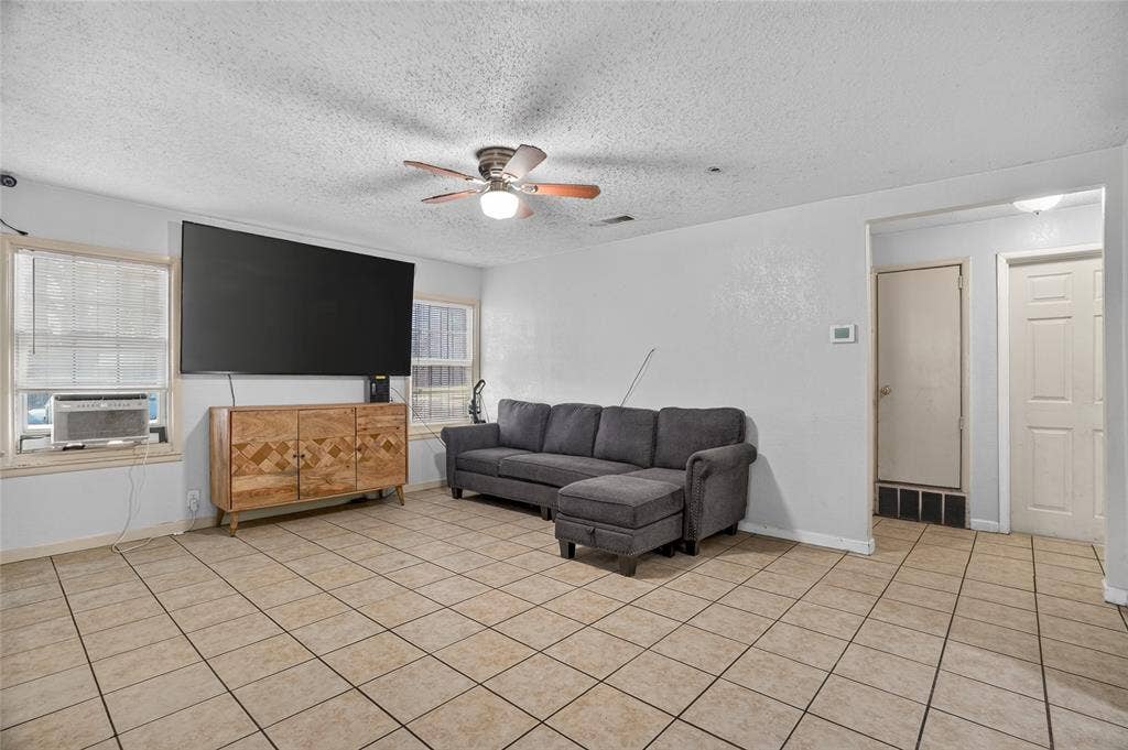 5800 Dallas Avenue, Fort Worth, TX 76112 Tile flooring, light gray walls, ceiling fan with integrated lighting, multiple windows, and a doorway with a paneled door