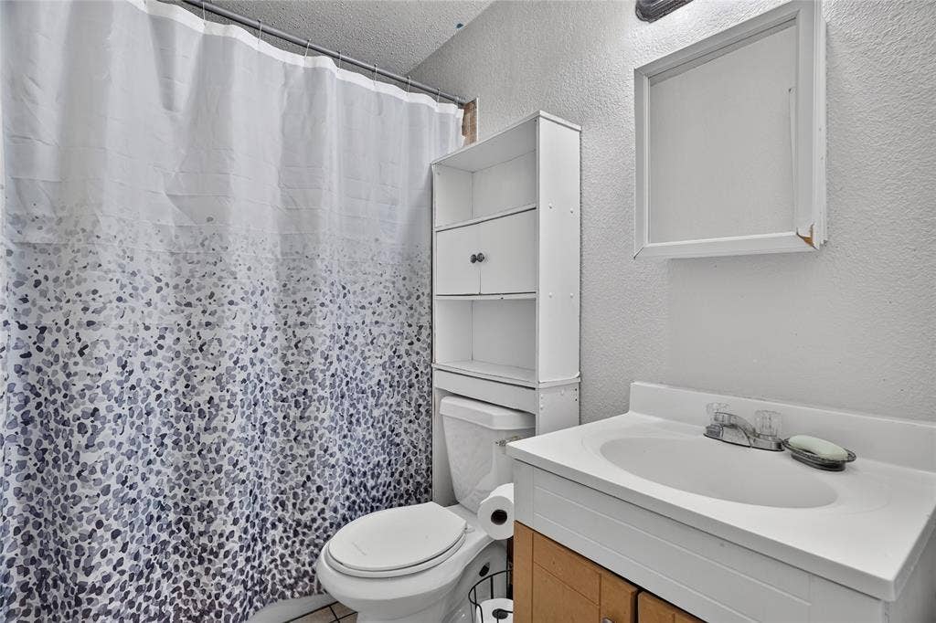 5800 Dallas Avenue, Fort Worth, TX 76112 White vanity with integrated sink and chrome-finish faucet, framed mirror, and built-in white storage shelving
