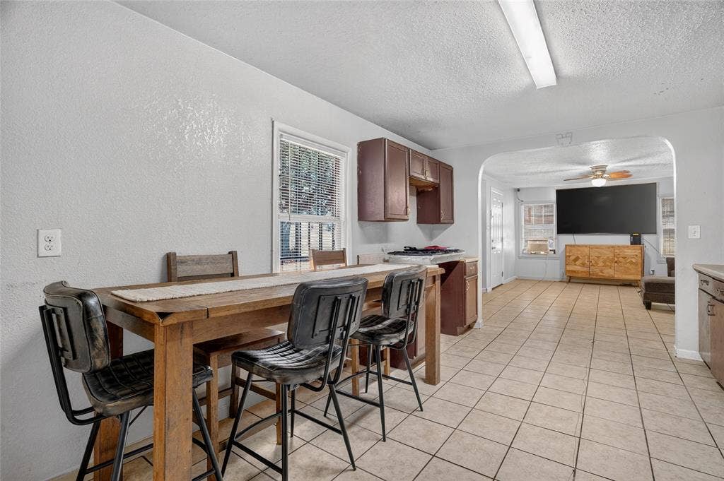 5800 Dallas Avenue, Fort Worth, TX 76112 Kitchen and dining area featuring tile flooring, a window with blinds, and wood-finish cabinetry