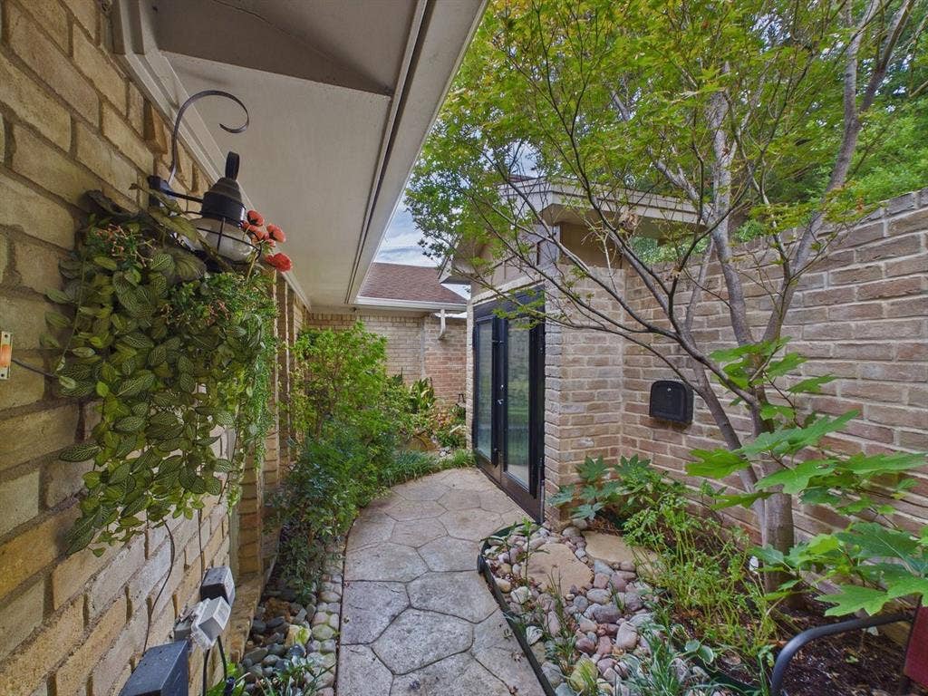 9335 Whittenburg Gate, Dallas, TX 75243 Brick exterior walls, stone-paver walkway, mature trees, built-in wall lantern, and glass-paneled double doors