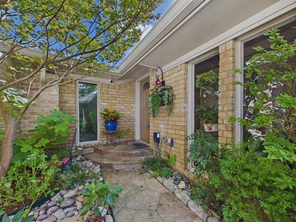 9335 Whittenburg Gate, Dallas, TX 75243 Brick exterior, concrete pathway, established landscaping, full-height windows, and a recessed entry