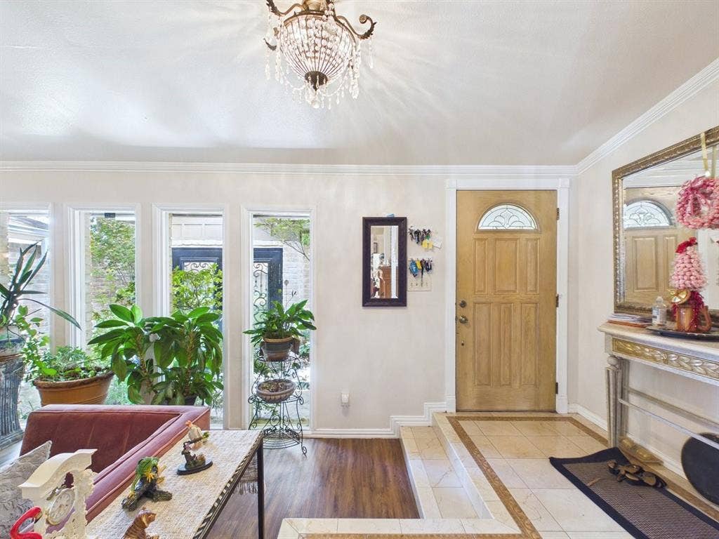 9335 Whittenburg Gate, Dallas, TX 75243 Entry foyer featuring a decorative chandelier, light wood-finish door with an arched glass insert, and a patterned tile floor with a wood-finish flooring transition