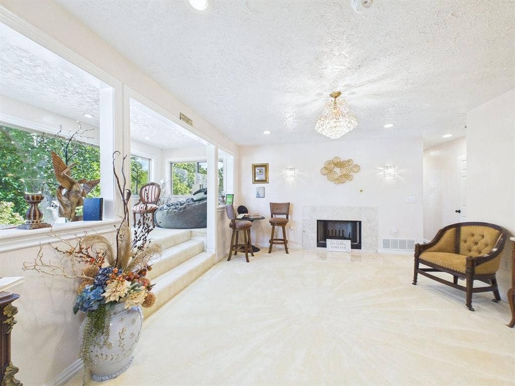 9335 Whittenburg Gate, Dallas, TX 75243 Recessed lighting, a decorative chandelier, and wall sconces illuminate the space, complemented by a tiled fireplace surround