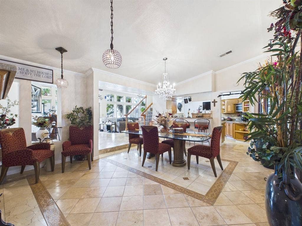 9335 Whittenburg Gate, Dallas, TX 75243 Vaulted ceiling with a chandelier, tile flooring with an accent border, integrated kitchen with a breakfast bar, and a staircase with a detailed railing