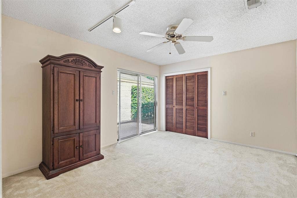 Sliding glass doors, track lighting, ceiling fan, and louvered bifold closet doors