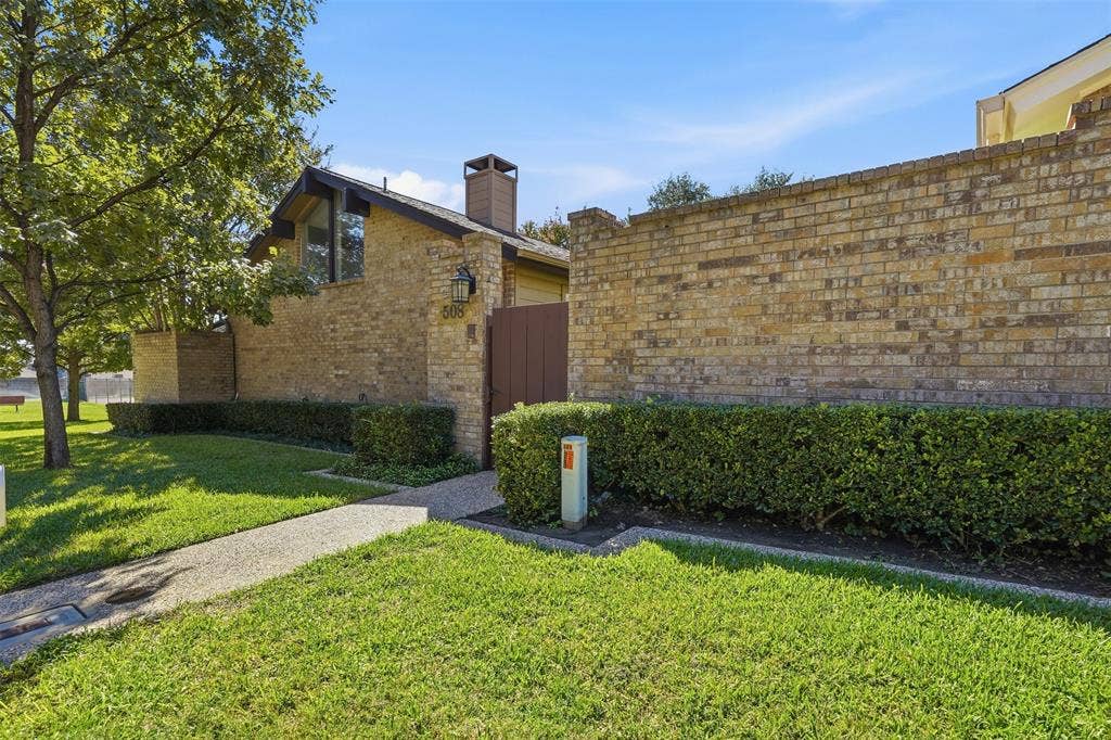 Brick exterior with a prominent chimney, a dark-toned front entry door, and a concrete walkway